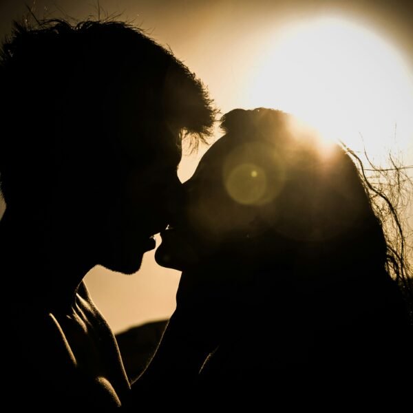 man and woman kissing under the sun